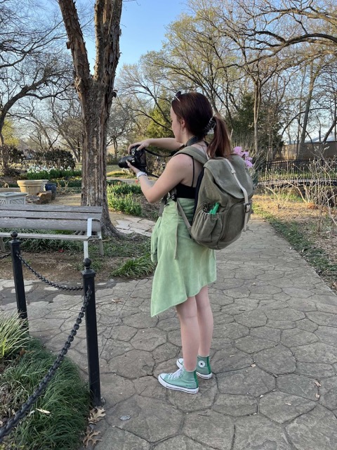 Taylor taking a photo during a photoshoot in a garden